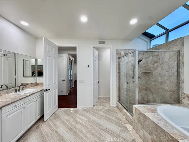 Main bathroom with dual vanities, jetted tub, and separate shower