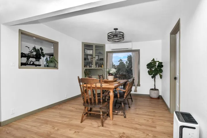 Dining room with light wood finished floors and a wall mounted AC