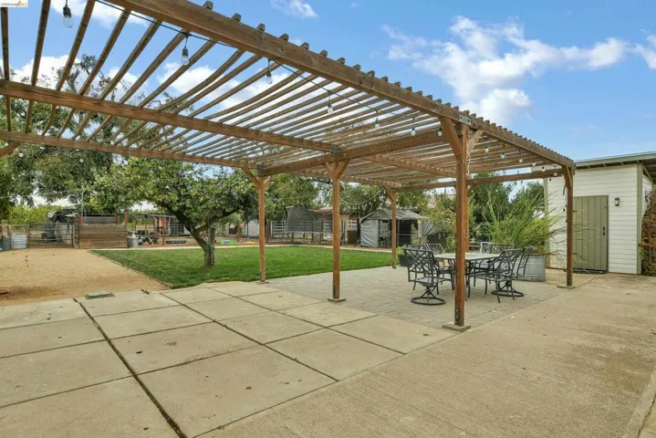 Fenced backyard featuring a shed, a playground, a patio area, outdoor dining space, and a pergola