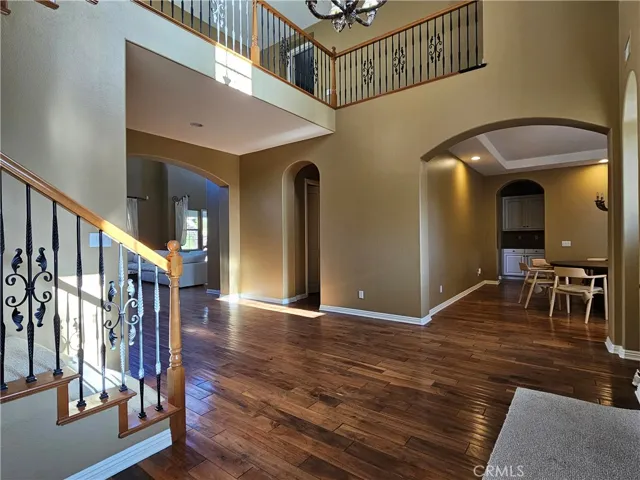 View of the main floor's open layout from the foyer, connecting the living room and dining room. Features hardwood floors and wrought iron staircase detail.