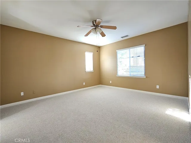 Expansive southwest upstairs room offering flexibility and comfort. This light-filled space features a neutral color palette, plush carpeting, and generous natural light from two windows with blinds. Includes a ceiling fan and central HVAC for comfort year-round. This versatile area is ideal for a serene primary bedroom suite, a convenient upstairs game room, or a private home office, ready for you to make your own.