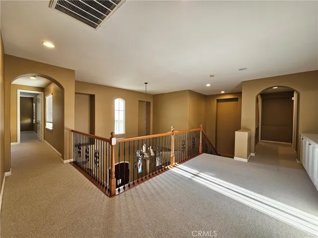 Discover this inviting upstairs open loft, an ideal flexible bonus space overlooking the main floor. The area features elegant wood and wrought-iron stair railings, abundant natural light, and convenient built-in white cabinetry for extra storage. With a neutral color palette and plush carpeting, this versatile space provides seamless flow to all upstairs bedrooms and is ready for you to enjoy.