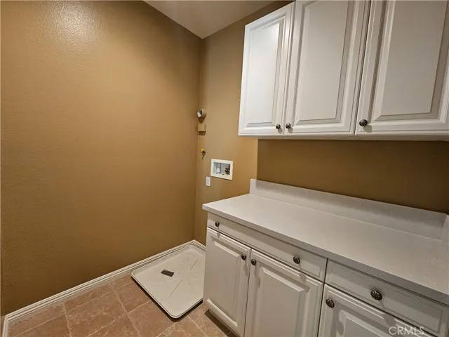 Enjoy the ultimate convenience of this dedicated upstairs laundry room. Thoughtfully designed to make chores a breeze, it features abundant white cabinetry, a spacious folding counter, and necessary utility hookups for your appliances.