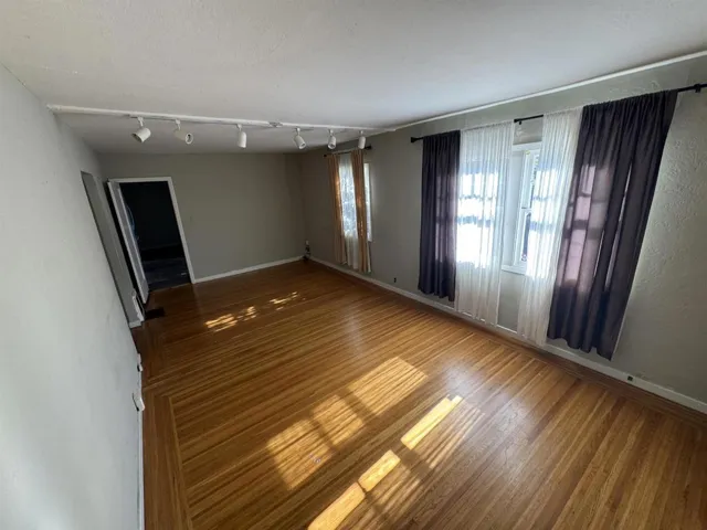 Unfurnished room with wood finished floors and track lighting