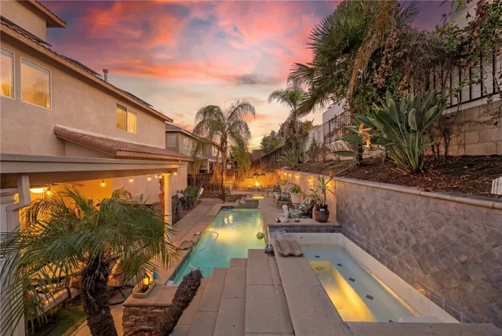 Night time shot of pool and jacuzzi in back yard