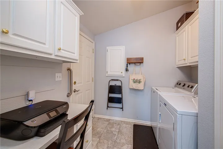 Multipurpose laundry room featuring cabinets galore, office work station and door to the 2-car garage.