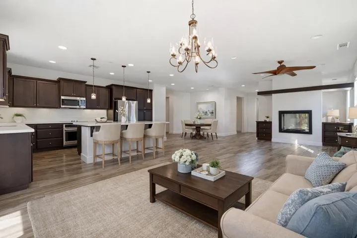Living area featuring light wood-type flooring, a chandelier, recessed lighting, ceiling fan, and a glass covered fireplace