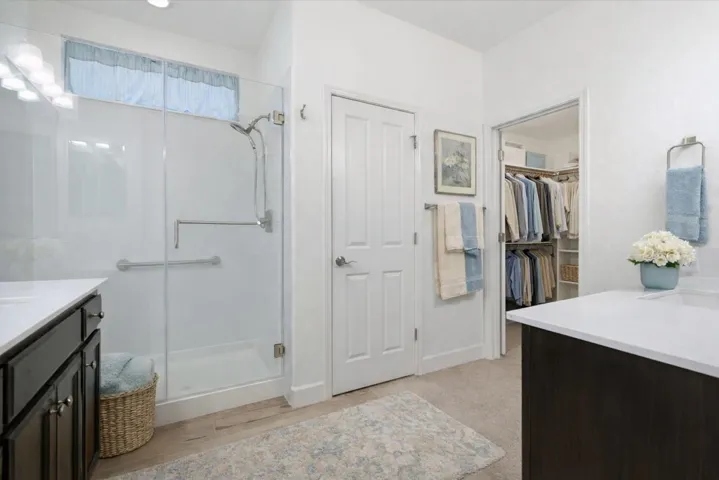 Full bathroom featuring vanity, a spacious closet, and a shower stall