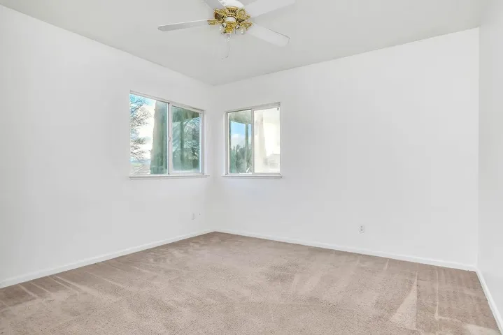 Empty room featuring light colored carpet and a ceiling fan