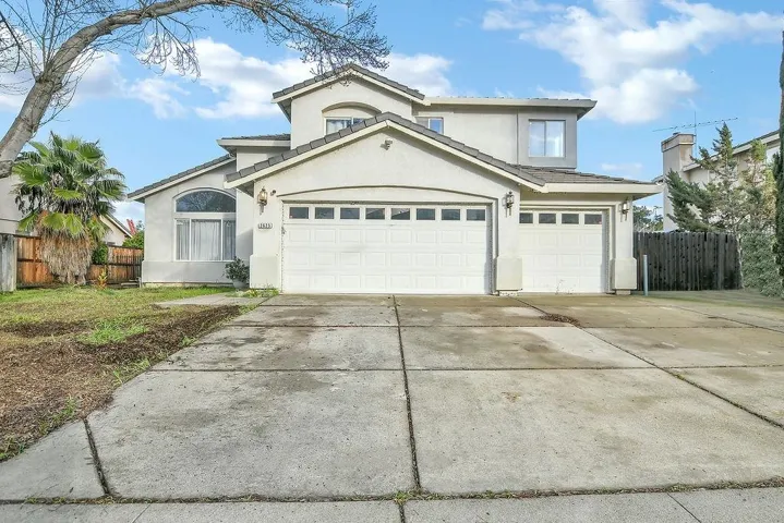 Traditional house featuring driveway, stucco siding, and a garage