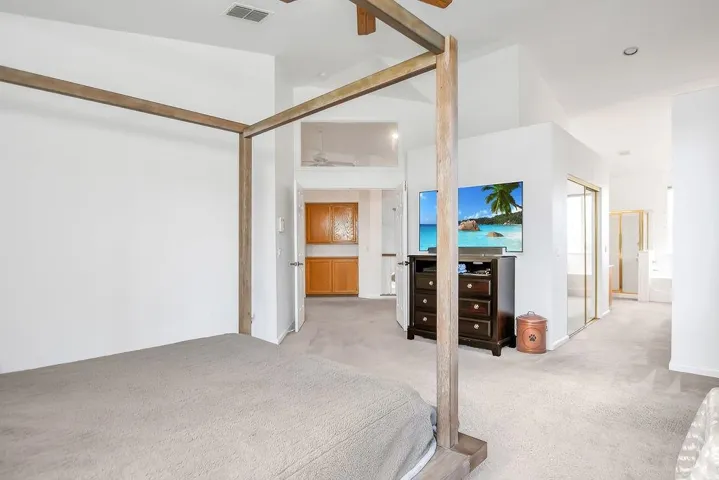 Carpeted bedroom with ensuite bathroom, a closet, and high vaulted ceiling