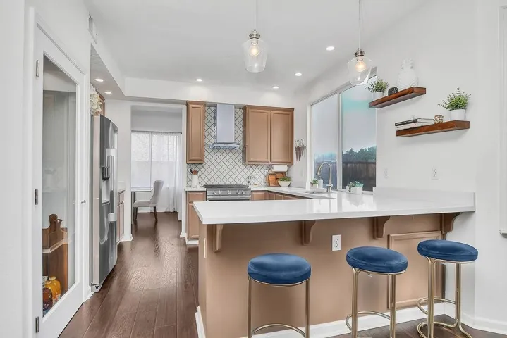 Kitchen featuring open shelves, decorative light fixtures, a peninsula, a breakfast bar area, and backsplash