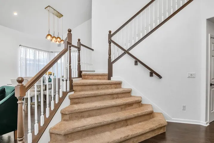 Stairs with wood finished floors and a towering ceiling