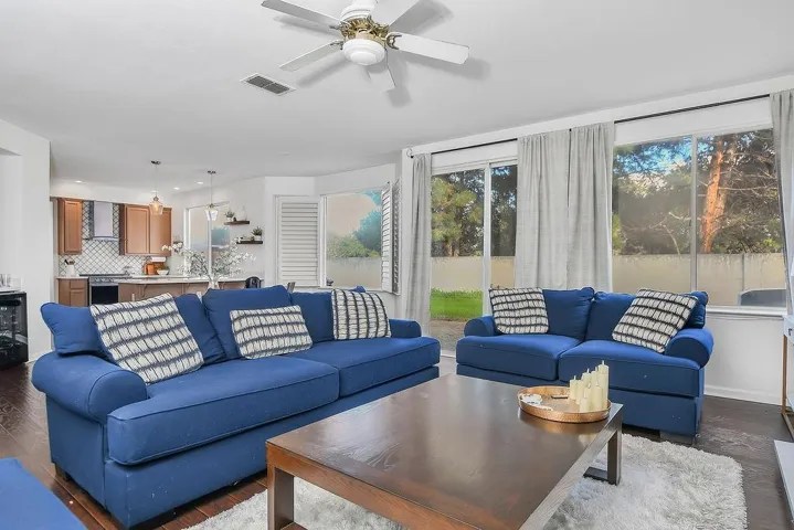 Living area with healthy amount of natural light, dark wood finished floors, ceiling fan, and wine cooler