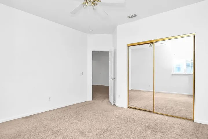 Unfurnished bedroom with carpet floors, ceiling fan, and a closet