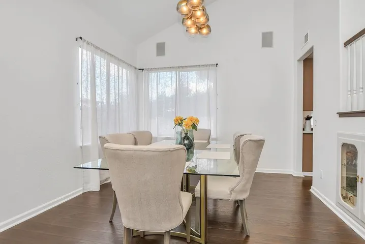 Dining area with dark wood-style floors and high vaulted ceiling