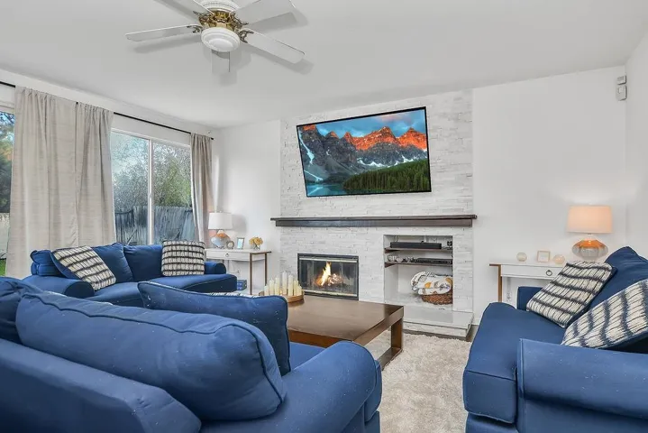 Living area featuring a stone fireplace and ceiling fan