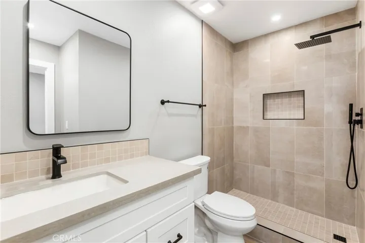 Updated bathroom featuring a walk-in shower with custom tile, niche shelving, and modern fixtures.