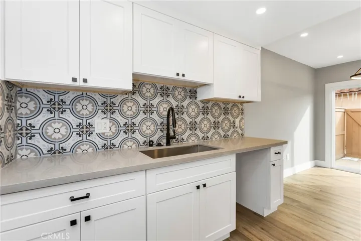 Close-up view of the kitchen showcasing quartz counters, custom tile backsplash, and modern hardware.