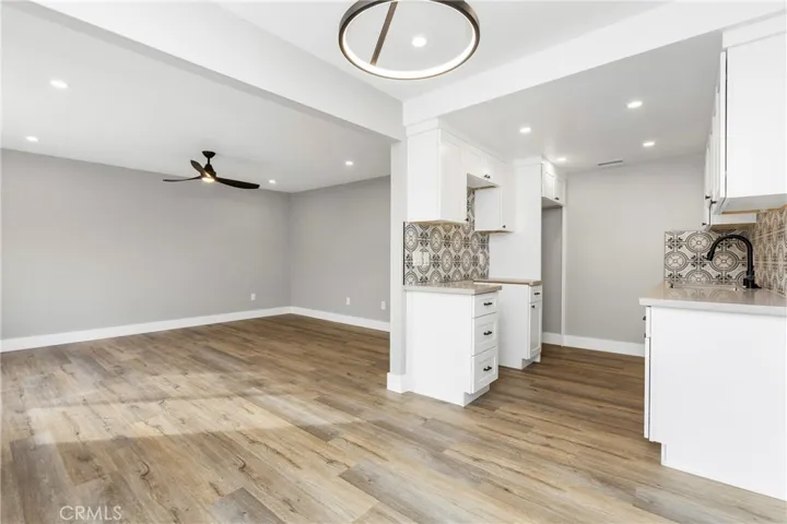 Open-concept living, dining, and kitchen area featuring wide-plank flooring, recessed lighting, and modern fixtures.