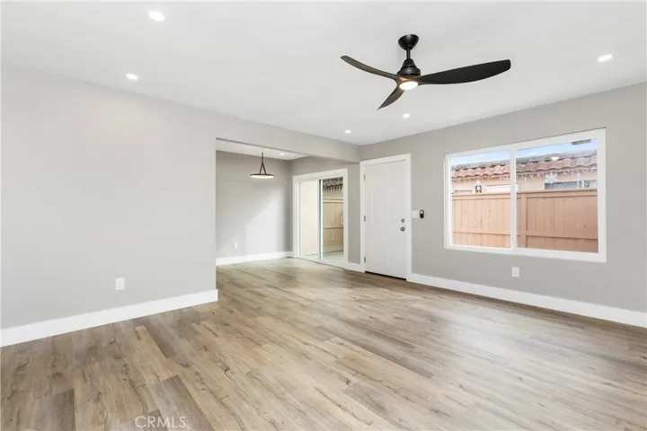 Bright, open living area featuring new flooring, recessed lighting, and a modern ceiling fan—ready for your personal touch.