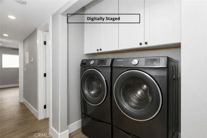 In-unit laundry area with full-size washer and dryer, upper cabinetry, and hallway access. Digitally staged.