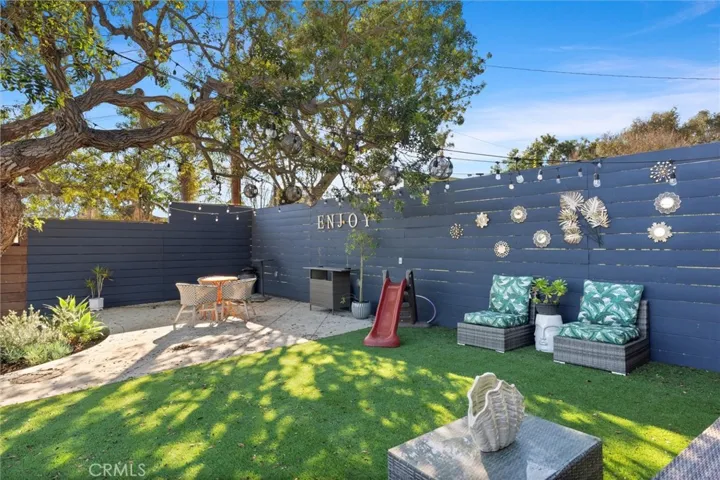 Top level of the backyard. Two different seating areas and a section of grass.