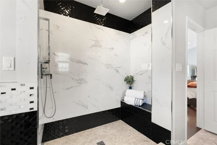 Large shower with an overhead rain faucet and shower seat. Custom tile throughout the ensuite bathroom.