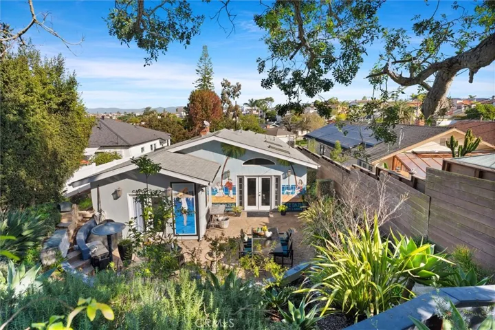 View of the backyard from the back wall. Levels of different stone lined patios, garden spaces and seating areas.