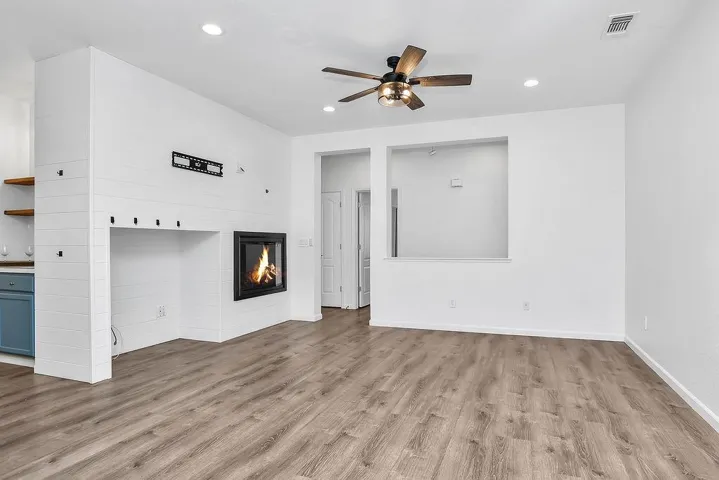 Unfurnished living room with light wood-style flooring, ceiling fan, a glass covered fireplace, and recessed lighting