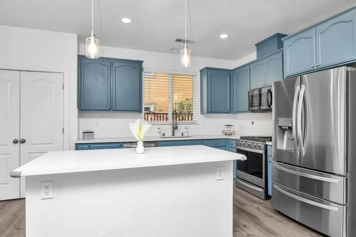 Kitchen featuring blue cabinetry, appliances with stainless steel finishes, pendant lighting, a center island, and recessed lighting
