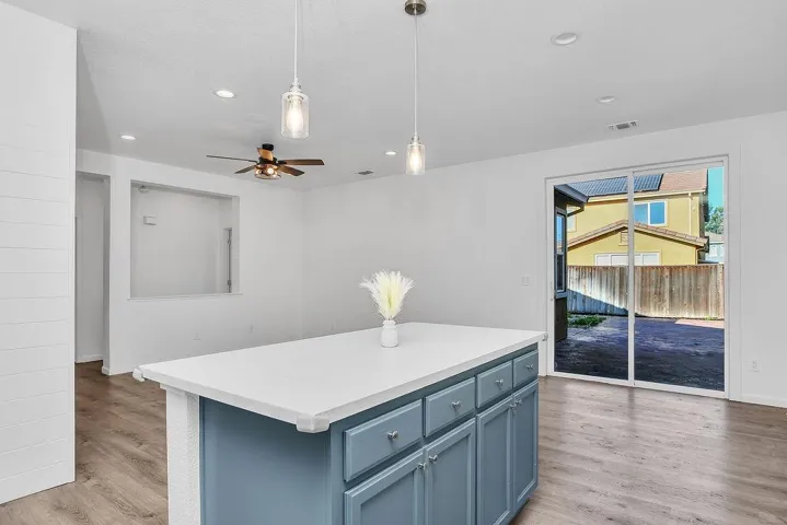Kitchen featuring blue cabinets, hanging light fixtures, a center island, light wood-style flooring, and recessed lighting