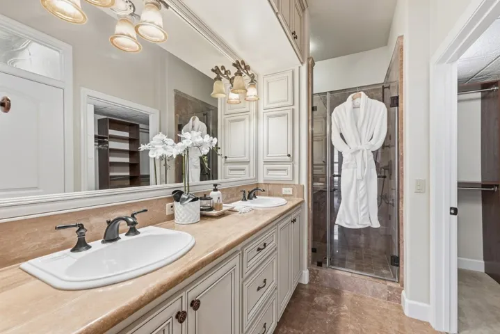 Full bath with a spacious closet, double vanity, a shower stall, and a chandelier