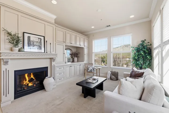 Living area featuring crown molding, light colored carpet, recessed lighting, and a lit fireplace