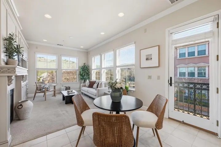 Dining room featuring crown molding, a fireplace with raised hearth, light tile patterned floors, light carpet, and recessed lighting