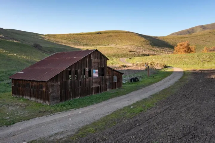 A storage barn with rolling hills (on property) in the background.