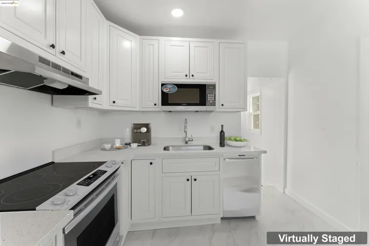 Kitchen with stainless steel appliances, light marble finish floors, and white cabinetry