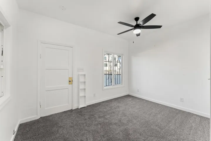 Spare room featuring dark carpet and a ceiling fan