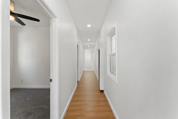 Hallway featuring light carpet, recessed lighting, and light wood-type flooring