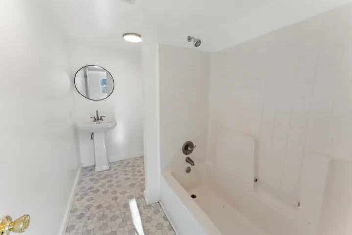 Bathroom with washtub / shower combination and light tile patterned floors