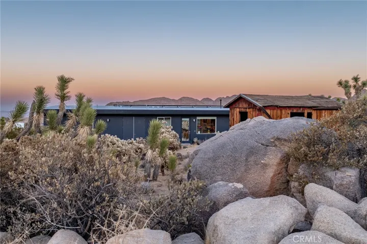 Entrance of house and original homestead peaking through boulders on the property