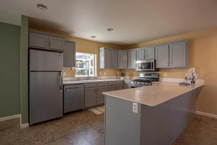 Open kitchen w/newly painted kitchen cabinets and stainless steel appliances.