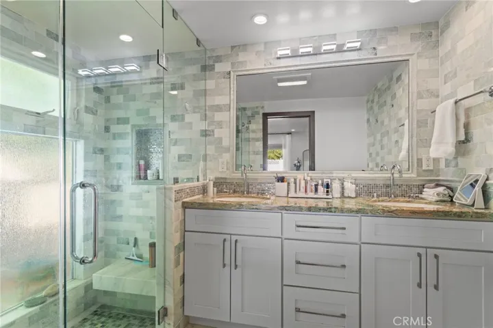 Bath 2 - features walk-in shower, double sinks, and adequate storage.