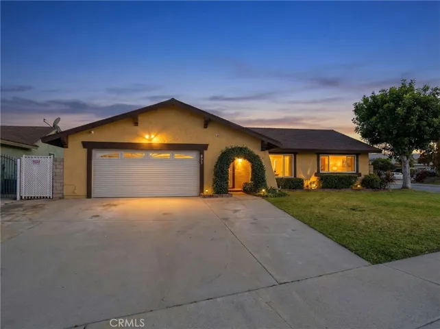 Twilight front exterior highlighting the arched entry, spacious driveway, and warm exterior lighting