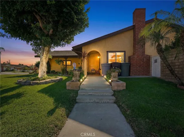 Dusk Exterior view with illuminated entry and mature landscaping