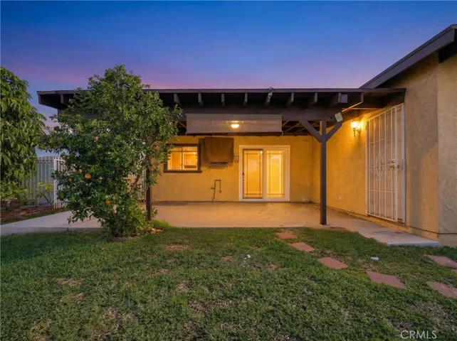 Twilight backyard view featuring a covered patio and warm exterior lighting