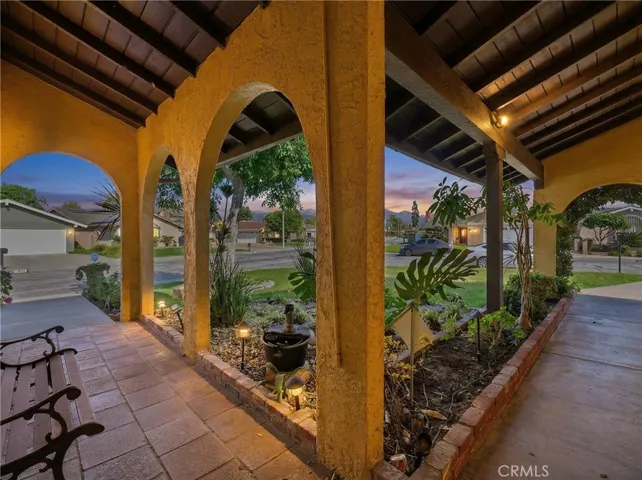 Twilight view of the covered front porch highlighting the arched entry and ambient landscape lighting