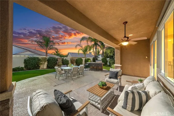 Spacious backyard with covered patio, BBQ island, and artificial turf. Digitally enhanced to mimic twilight