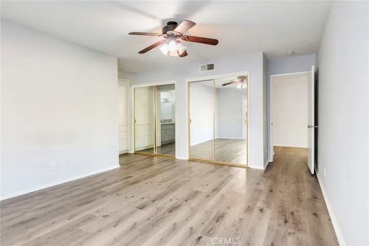 Primary bedroom with dual, mirrored closets and ample storage.