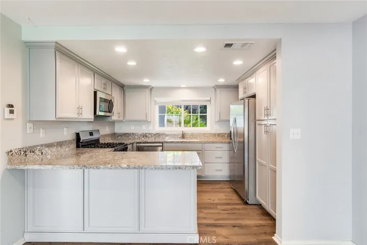 Stunning kitchen with gray cabinetry and updated stone countertops. The kitchen features a window looking out into the front yard.